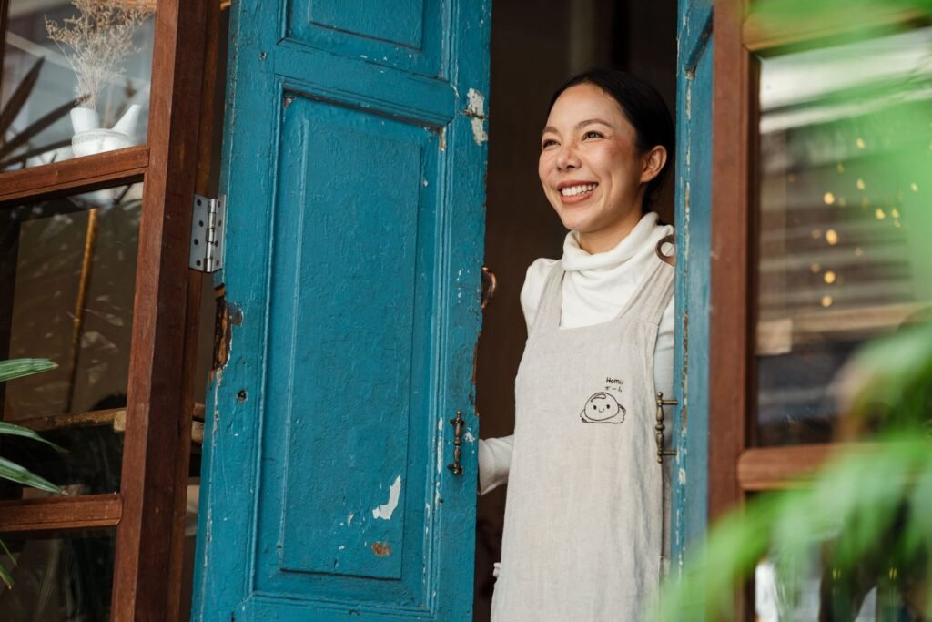 Lojista sorrindo na porta do seu comércio, pronta para receber clientes, exemplo de negócio que precisa de um site para comércio em Bragança Paulista